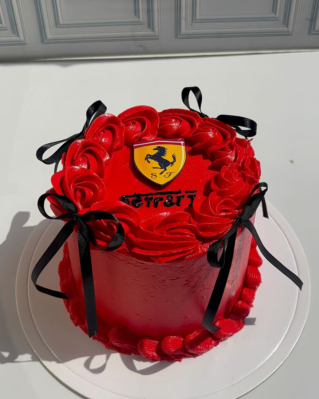 Torta roja de rosetas con lazos negros y escudo de Ferrari